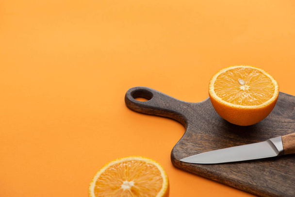 fresh juicy orange halves on cutting board with knife on colorful background - Foto, afbeelding