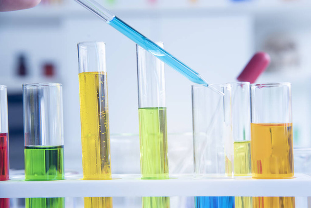 Tubos de ensayo de vidrio que contienen muchas sustancias químicas en un laboratorio, una reacción científica de diferentes colores con líquidos de color
 - Foto, Imagen