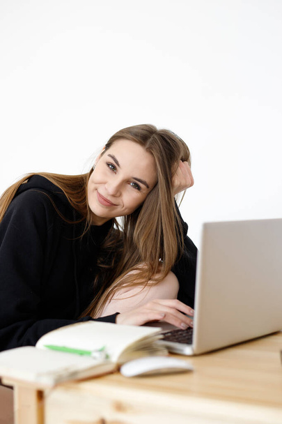 Inteligentna młoda kobieta zadowolona z nauki języka podczas kursów online z wykorzystaniem netbooka, uśmiechnięta studentka z notatnikiem odrabiająca lekcje, bloger szuka informacji w Internecie - Zdjęcie, obraz