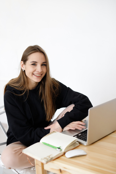 Έξυπνη νεαρή γυναίκα ικανοποιημένη με την εκμάθηση γλωσσών κατά τη διάρκεια των online μαθημάτων χρησιμοποιώντας ένα netbook, χαμογελαστή μαθήτρια με ένα σημειωματάριο που κάνει την εργασία της, μια blogger ψάχνει για πληροφορίες στο Διαδίκτυο - Φωτογραφία, εικόνα