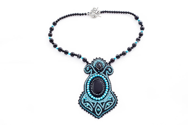 Beaded necklace with oval turquoise pendant isolated on white background. Female accessories, decorative ornaments and jewelry. Fashion and style concept. - Photo, Image