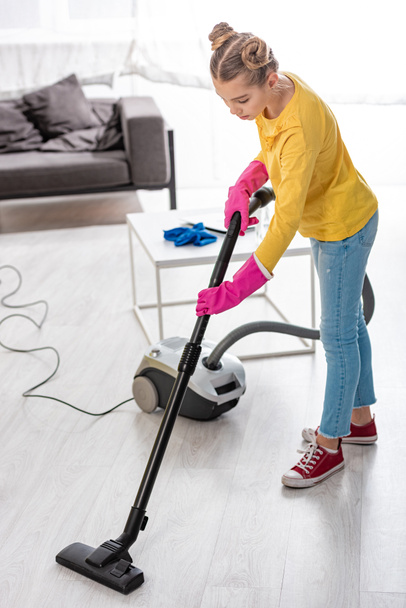 Child cleaning up with vacuum cleaner in living room - Valokuva, kuva