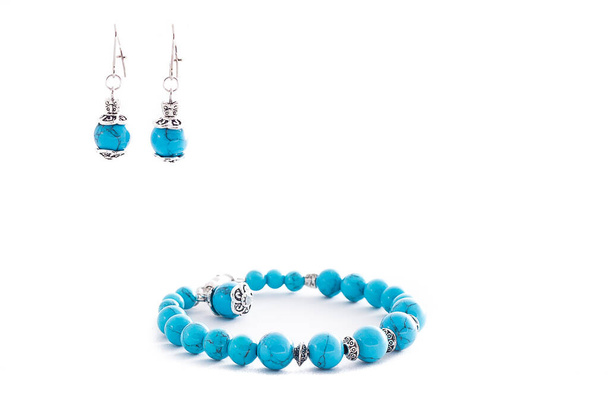 Set van turquoise oorbellen en armband geïsoleerd op witte achtergrond. Vrouwelijke accessoires, decoratieve ornamenten en sieraden. Mode- en stijlconcept. - Foto, afbeelding