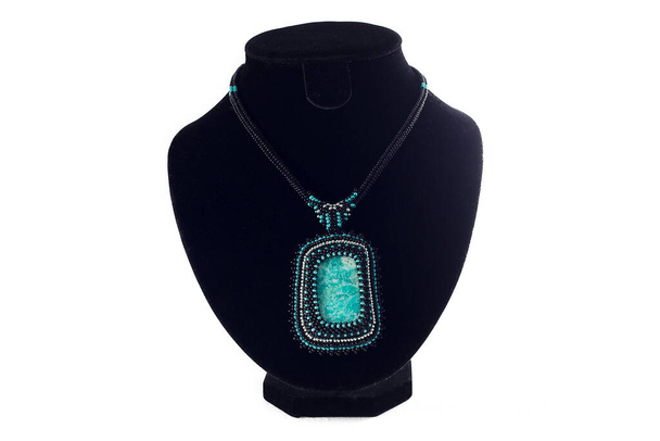 Beaded necklace with turquoise pendant on black velvet bust isolated on white background. Female accessories, decorative ornaments and jewelry. Fashion and style concept. - Photo, Image