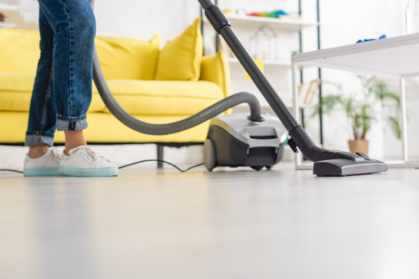 Cropped view of woman with vacuum cleaner near coffee table in living room - Φωτογραφία, εικόνα