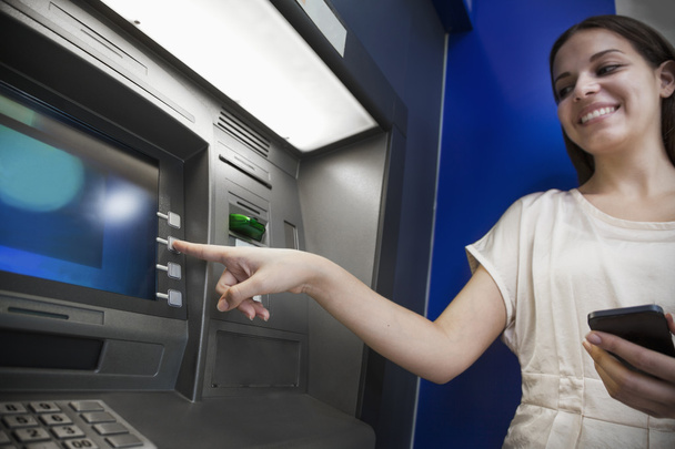 Nainen nostaa rahaa pankkiautomaatista
 - Valokuva, kuva
