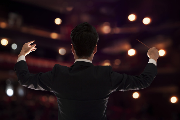 Conductor with baton raised at a performance - Foto, Imagen