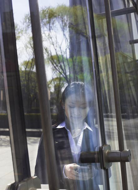 Geschäftsfrau telefoniert auf der anderen Seite einer Glastür - Foto, Bild