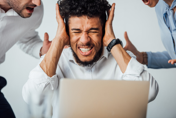 Селективный фокус африканского американского бизнесмена, закрывающего уши перед ссорящимися коллегами в офисе
  - Фото, изображение