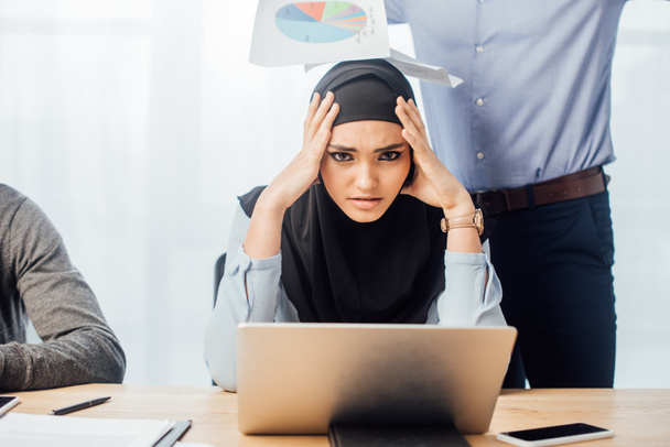 Sad arabian businesswoman looking at camera near colleagues in office  - 写真・画像