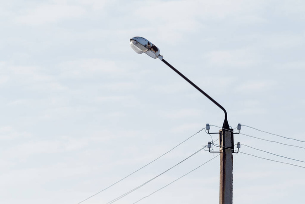 Poste eléctrico con lámpara de cables contra el cielo
. - Foto, Imagen