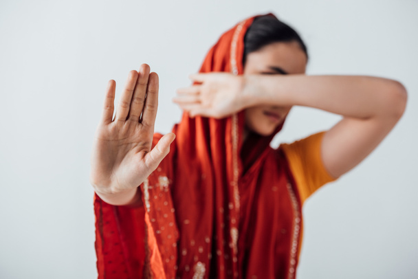 Selektiver Fokus der Frau im Sari zeigt Stoppschild und verdeckt Gesicht isoliert auf grau - Foto, Bild