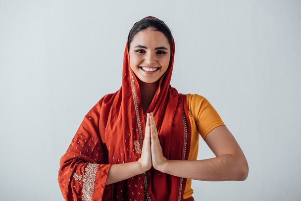 glimlachende indiaanse vrouw met speler handen kijken naar camera geïsoleerd op grijs - Foto, afbeelding