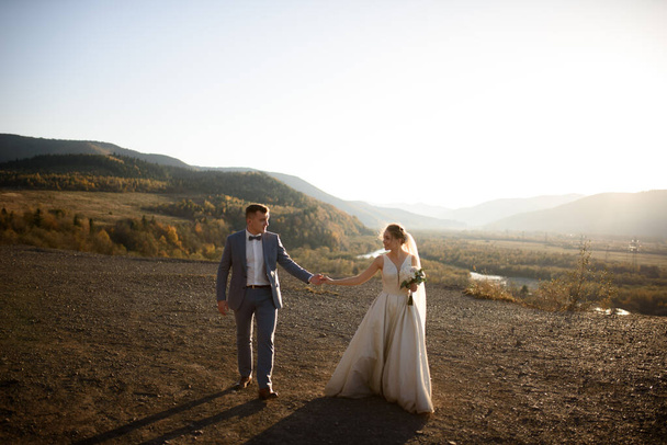 Esküvői fotózás a menyasszony és a vőlegény a hegyekben. Fotózás naplementekor. - Fotó, kép