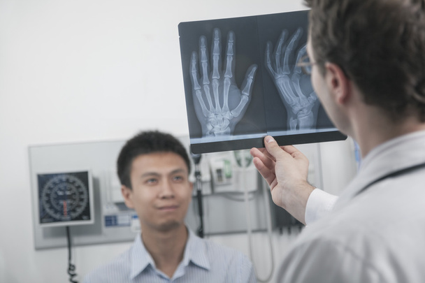 Врач смотрит на рентген костей рук пациентов
 - Фото, изображение