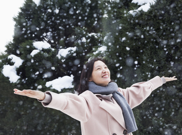 Femme avec les bras tendus sentant la neige
 - Photo, image
