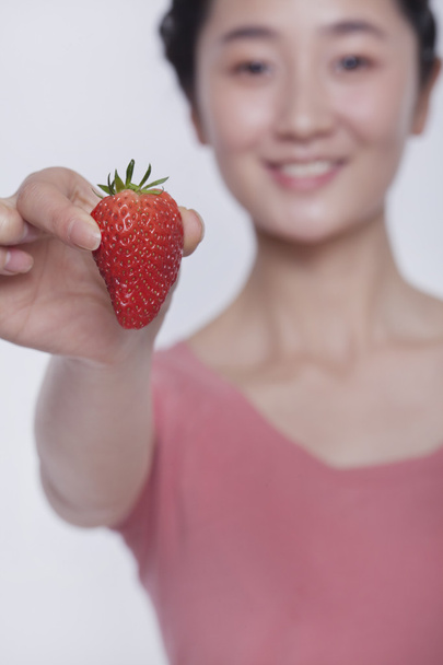 Femme en chemise rose tenant et montrant une fraise
 - Photo, image