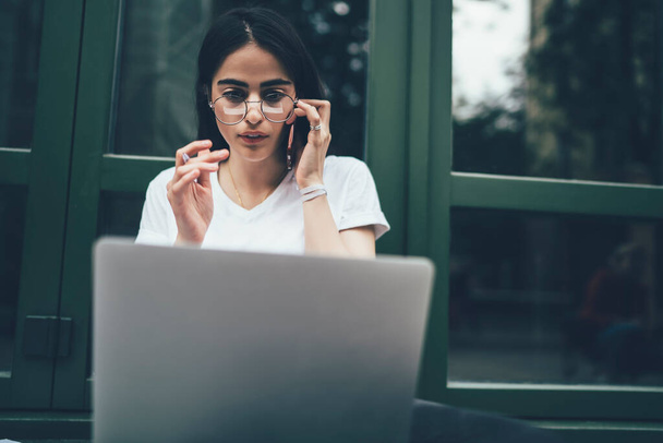 Amazed female software developer in optical spectacles wonder with mistake in program code calling to colleague for online consultancy while working remotely, skilled woman reading shocked news - Foto, afbeelding