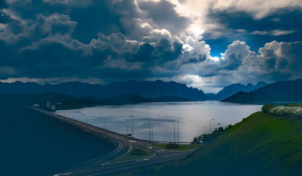 Вечірній пейзаж на греблі Раджапрабха Сурат Тані, Таїланд. Масивні хмари над гірським пейзажем. Вулиця на краю греблі Раджапабха, водний фронт. Синій колір тонусу коригується зображення. - Фото, зображення