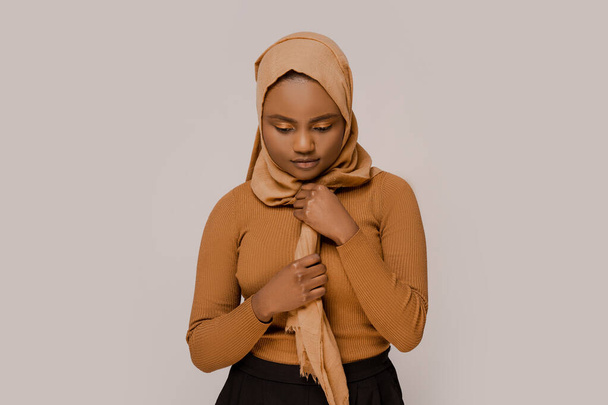 Moslim vrouw Afrikaanse etniciteit in traditionele hijab met kalme droevige emotie voor te bereiden op het bidden over witte studio achtergrond. Mensen en religie. - Foto, afbeelding