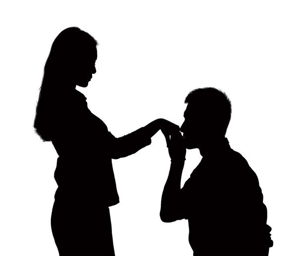 Silhouette of man on one knee, kissing woman's hand - 写真・画像