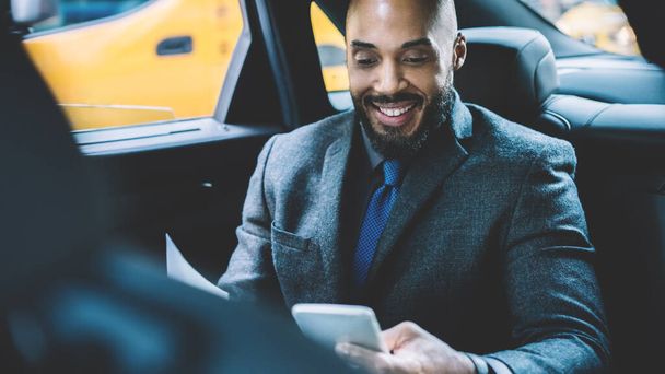 Cheerful male person dressed in elegant wear reading received email with good news about signing contract between two corporate enterprises, happy successful lawyer enjoying time for chatting in car - Foto, immagini