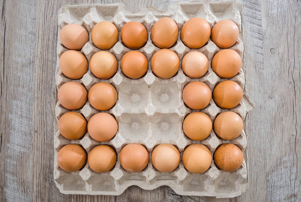 Kippeneieren in een kartonnen doos op een houten tafel zonder vier eieren. - Foto, afbeelding