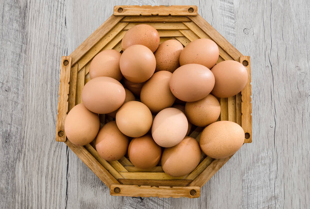 Αυγά κοτόπουλου σε ξύλινο πιάτο πάνω σε ξύλινο τραπέζι. Θέα από ψηλά. Κοντινό πλάνο. - Φωτογραφία, εικόνα