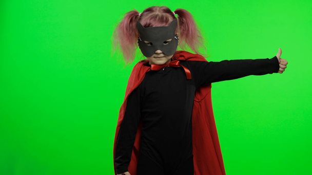 Grappig kind meisje in kostuum en masker speelt super held. Nationale superheldendag - Foto, afbeelding