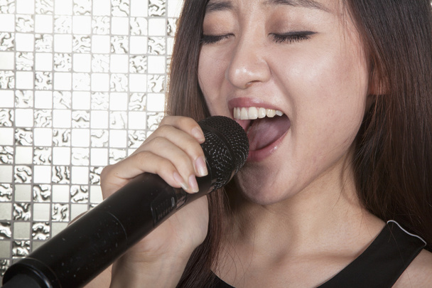 młoda kobieta śpiewa do mikrofonu w karaoke - Zdjęcie, obraz