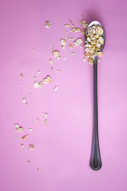 νιφάδες βρώμης σε κουτάλι σε νιφάδες βρώμης φόντο με κενό χώρο για το κείμενό σας, υγιεινό πρωινό, διατροφή - Φωτογραφία, εικόνα