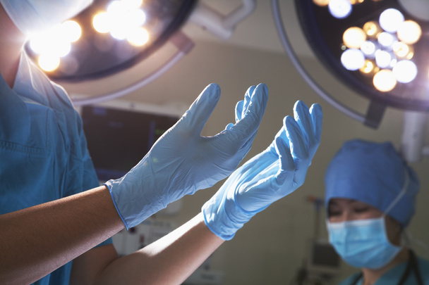 Mani in guanti chirurgici in sala operatoria
 - Foto, immagini