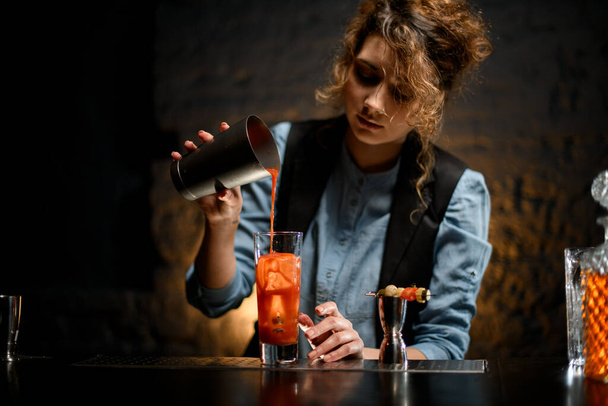 camarera hembra vierte jugo de tomate en un vaso con hielo
. - Foto, Imagen
