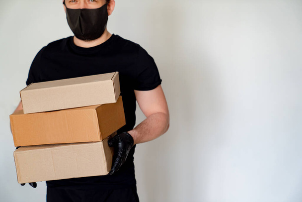 Delivery man in black hold cardboard boxes - 写真・画像