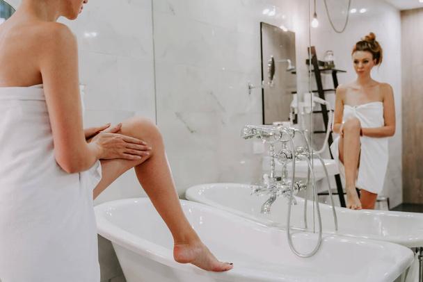 Beyaz havluyla duş alan güzel bir kadın cildine krem sürer. Ev yapımı vücut bakımı. spa tedavileri - Fotoğraf, Görsel