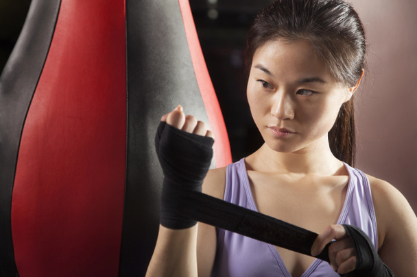 Жінка-боксер обгортає зап'ястя в спортзалі
 - Фото, зображення