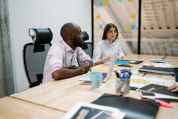 現代のオフィスで働く多様な男性と女性の同僚は、会社の財務計画を作成し、インテリジェントパートナーは、デスクに座って、生産的なビジネス戦略のためのアイデアを議論します - 写真・画像