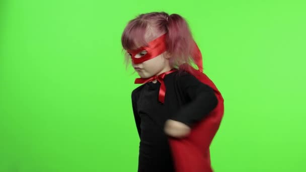 Zabawna dziewczynka w kostiumie i masce gra superbohatera. Narodowy Dzień Superbohatera - Materiał filmowy, wideo