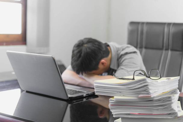 Empresario dormido en el escritorio de la oficina con la calculadora de hojas de finanzas, que está teniendo un mal dolor de cabeza, estrés y el concepto de exceso de trabajo
. - Foto, Imagen