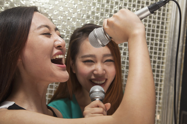 φίλες τραγουδώντας σε ένα μικρόφωνο καραόκε - Φωτογραφία, εικόνα