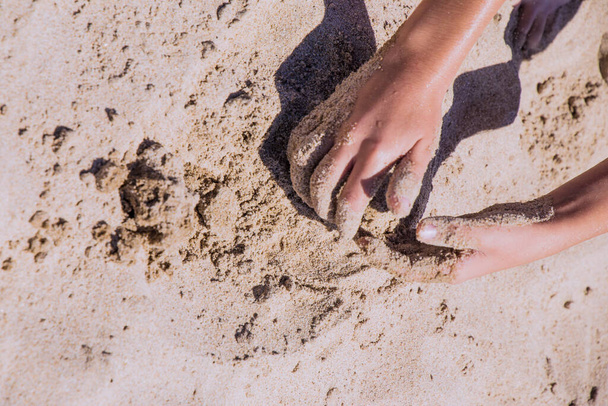 Manos de niños jugando en la arena con espacio para poner letras
 - Foto, imagen