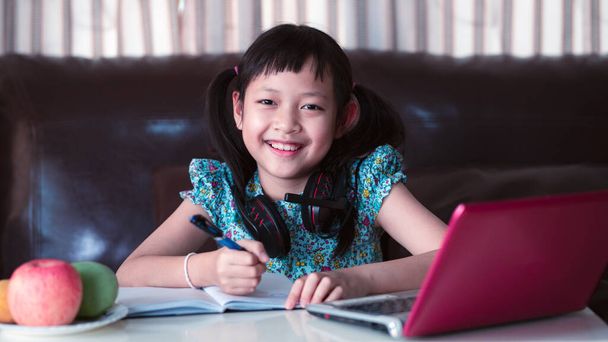 Cute asian little child girl studying  online lesson at home, social distance during quarantine, online education concept.16:9 style - Photo, Image