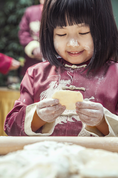 Маленькая девочка делает пельмени в традиционной одежде
 - Фото, изображение
