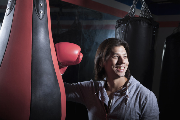 człowiek w boks gimnastyka, opierając się na worek treningowy - Zdjęcie, obraz