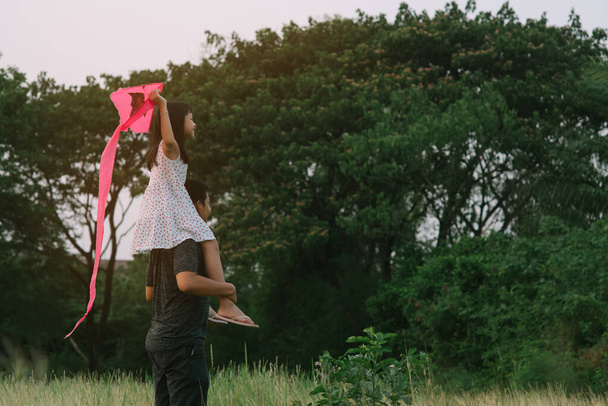 Asiatique petite fille enfant chevauchant sur les épaules du père dans le fond naturel vert avec tenant le kite.16 : 9 style
 - Photo, image
