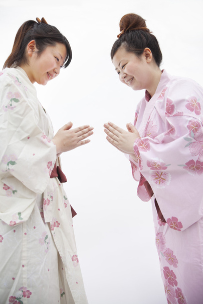 Nainen japanilaisissa kimonoissa kumartamassa toisiaan
 - Valokuva, kuva