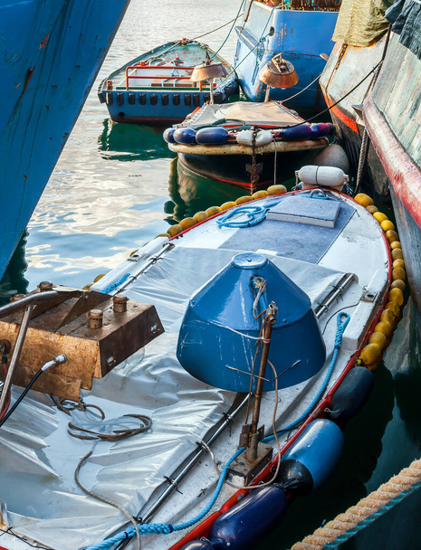 Drei farbige Boote mit Suchscheinwerfern, die zwischen Rümpfen von Fischerbooten vertäut sind - Foto, Bild