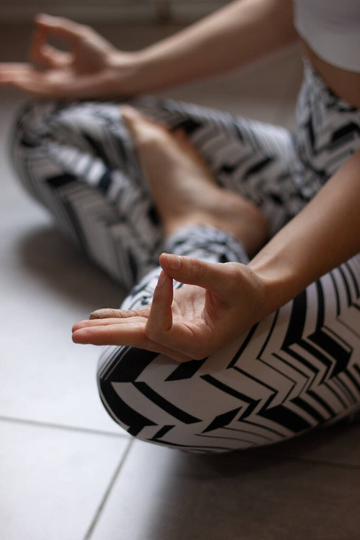 Vista de cerca de la joven hermosa mujer haciendo yoga por la mañana después de despertarse en casa. Modelo femenino sentado con las piernas cruzadas en pose Easy, postura Sukhasana y meditando
. - Foto, imagen