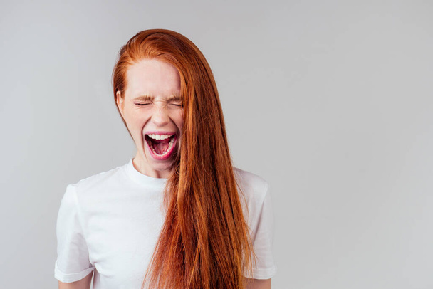 redhaired ginger student woman with open mouth and bad teeth - Foto, afbeelding