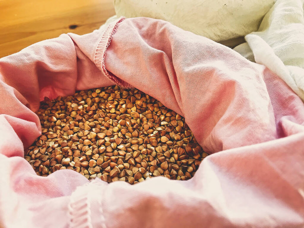 Organic buckwheat grain in reusable bag close up. Groceries in reusable textile bags on wooden table. Plastic free delivery from bulk store. Zero waste shopping. Ban plastic - Fotó, kép